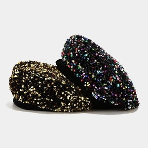 Detail of sparkly champagne gold and multi-color sequin berets on black fabric