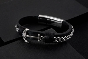 Macro shot of anchor charm and steel chain on black woven leather bracelet