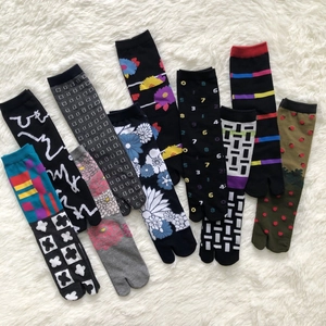 Flat lay of colorful Tabi socks with floral and strawberry jacquard patterns on white plush