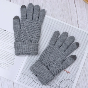 Close-up of grey knitted gloves with touchscreen tips on a rustic desk with props