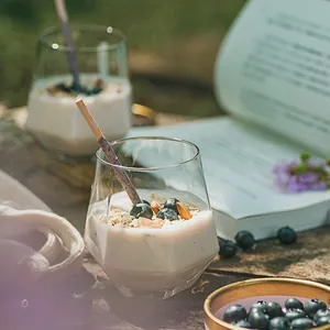 Detailed view of a geometric glass cup filled with yogurt and nuts in a natural outdoor setting