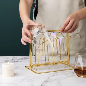 Detail of a golden metal cup holder organizing hexagonal iridescent glass cups on a desk