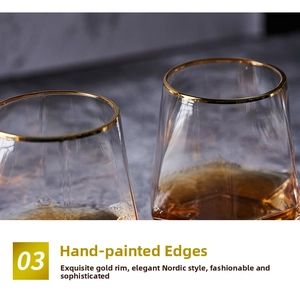 Close-up of gold-rimmed geometric glass cups with amber beverage on dark surface