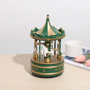 Boîte à musique carrousel vintage en bois vert foncé avec détails dorés sur bureau