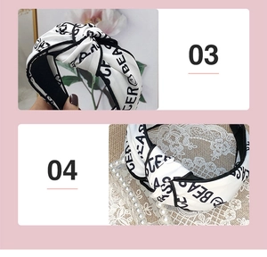 Detail of white knotted satin headband with black piping and printed letters pattern