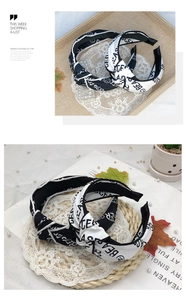 Close-up of wide-brimmed knotted fabric headbands with black and white letter patterns
