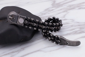 Detailed macro shot of vintage silver skull charms on a black braided leather punk bracelet