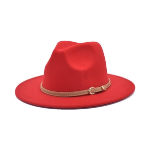 Detail of red fedora hat with a light brown leather band and golden buckle finish