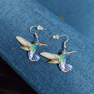 Detailed shot of vibrant hummingbird drop earrings with blue and green gradients