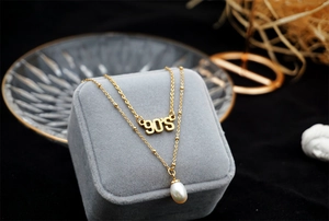 Close-up of double-layer gold necklace with 90'S letter charm and white pearl pendant