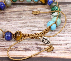Detalle de pulsera de yoga con piedras imperiales de colores y colgante de palmera