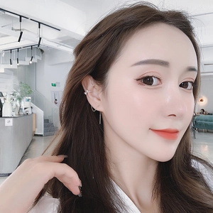 Primo piano di un ear cuff in argento con zirconi luccicanti indossato sull'orecchio