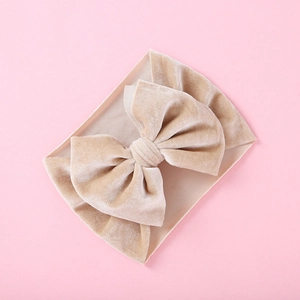 Detailed macro of a soft champagne velvet bow on a ribbed elastic baby headband