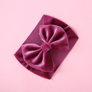Detail view of large burgundy velvet bow on an elastic bohemian baby headband