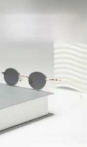Detail of vintage round metal sunglasses with gold wavy temples on a grey book background