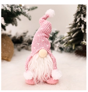 Close-up of pink knitted Christmas gnome with white heart pattern and soft plush beard