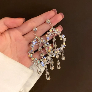 Detail of silver drop earrings featuring crystal rhinestones and hollow floral fringe