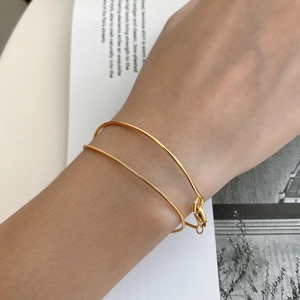 Macro view of minimalist 18K gold-plated double-layer snake chain and sleek ring bracelet