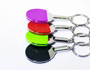 Close-up of four colorful mini table tennis racket keychains in purple, red, green, and black