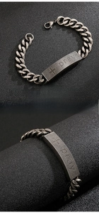 Macro detail of vintage steel tank chain bracelet featuring a cross and pray engraving