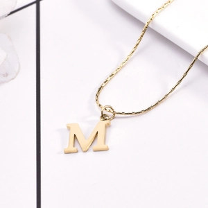 Detailed close-up of golden letter M pendant with a smooth snake chain necklace