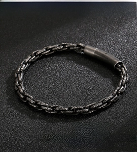 Makroaufnahme eines industriellen Vintage-Armbands aus 316L-Edelstahl auf schwarzem Sand