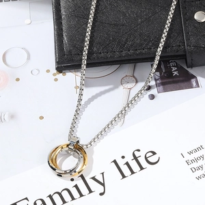 Close-up of interlocking tricolor steel rings pendant with small crystal on textured chain