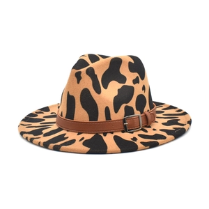 Detail of wide brim fedora hat featuring cow print pattern and leather band with metal buckle