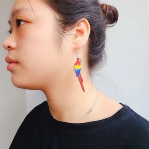Close-up of vibrant acrylic macaw parrot earrings worn on model for a trendy bird style