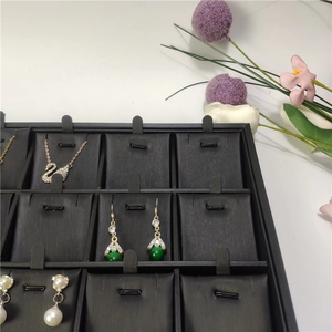 Detail view of a black 24-compartment jewelry tray for necklace and pendant display