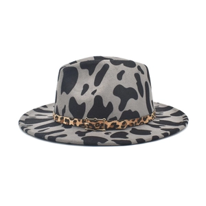 Dettaglio del cappello fedora grigio con stampa mucca, fascia leopardata e fibbia oro