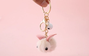 Close-up of cute beige and pink plush rabbit keychain with gold ring and white bell