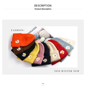Detailed flat lay of nine colorful knitted beanie hats featuring daisy embroidery detail