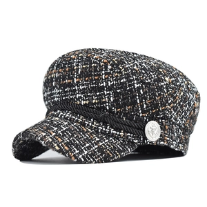 Detailed macro of tweed wool newsboy cap featuring silver anchor button and decorative rope