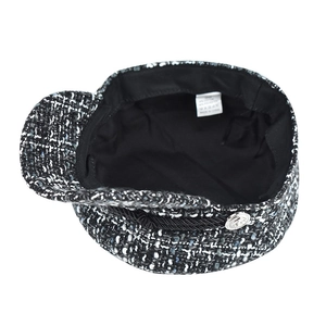 Detail of tweed newsboy cap showing metallic buttons and internal material wash label