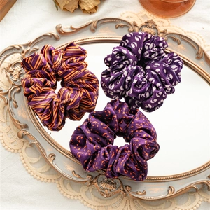 Detail of Halloween velvet hair scrunchies with pumpkin and ghost patterns on a vintage tray