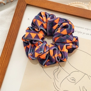 Artistic close-up of velvet Halloween scrunchie with orange and purple triangle pattern