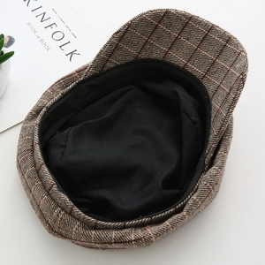 Detail view of the brown plaid newsboy cap showing the black lining and quality craft