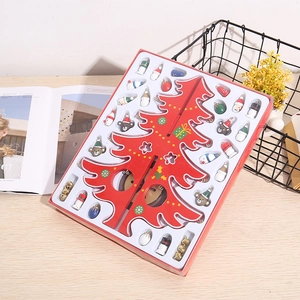Detail of DIY red wooden Christmas tree with mini painted ornaments on a wooden desk