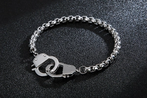 Detailed shot of silver stainless steel handcuff charm bracelet on a textured background