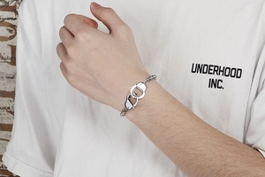 Close-up of a trendy silver stainless steel handcuff bracelet worn by a person on a white tee