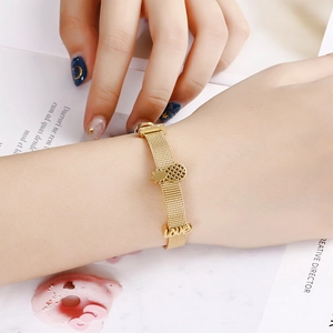 Gold mesh strap bracelet with pineapple charm and 'love' lettering on a female wrist