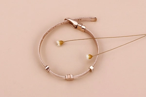Detailansicht eines roségoldenen Mesh-Armbands mit floralen und glitzernden Schiebern