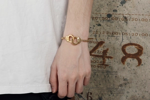Detail of gold-tone stainless steel handcuff link bracelet worn on a wrist