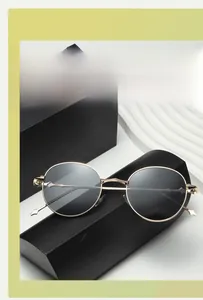 Detail of round gold metal sunglasses with dark lenses on a luxury leather case