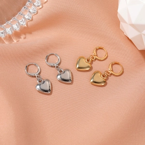 Gros plan détaillé des boucles d'oreilles cœur en or et argent sur satin rose doux
