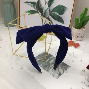 Elegant navy blue velvet double bow headband displayed with decorative accessories