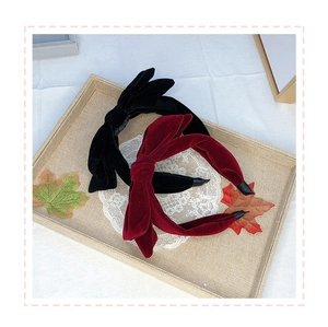 Close-up of black and burgundy velvet double bow headbands on a woven tray