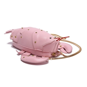 Detailed shot of pink lobster handbag featuring gold studs and elegant chain strap