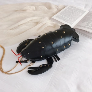 Black PU leather lobster shaped bag with gold studs and chain strap on a white background